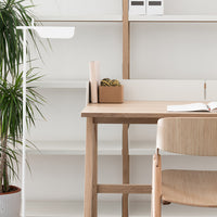 Light wood desk with a natural finish, paired with a soft beige chair against a minimalistic white backdrop.