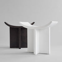 "Modern black and white stools with minimalist curved designs, showcasing sleek matte finishes."