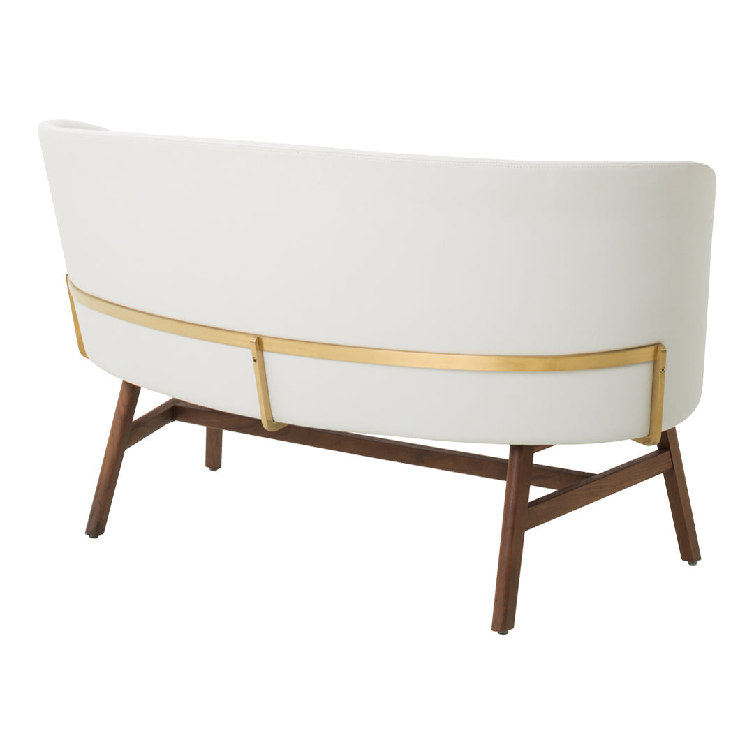 White curved back sofa with gold accents and wooden legs. Elegant, modern design with minimalistic aesthetics.