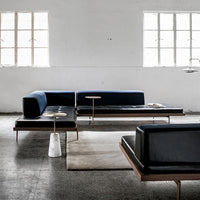 Modern sectional sofa in deep blue and black leather with sleek wooden accents, set against a neutral backdrop.