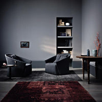 Dark gray chairs on a rich red patterned rug against a sleek gray wall, creating a modern, stylish ambiance.