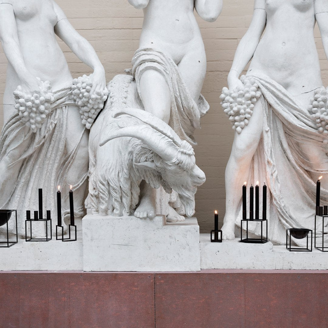 "Elegant white marble sculptures with subtle textures, almond-toned backdrop, and sleek black candle holders."