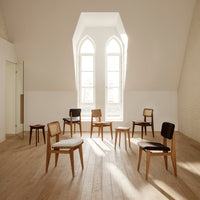 Natural wood chairs in light and dark finishes, featuring minimalist designs and subtle textures, set on a warm wood floor.