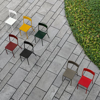 Colorful metal chairs in white, yellow, green, red, black, and brown arranged on a patterned stone patio with greenery.