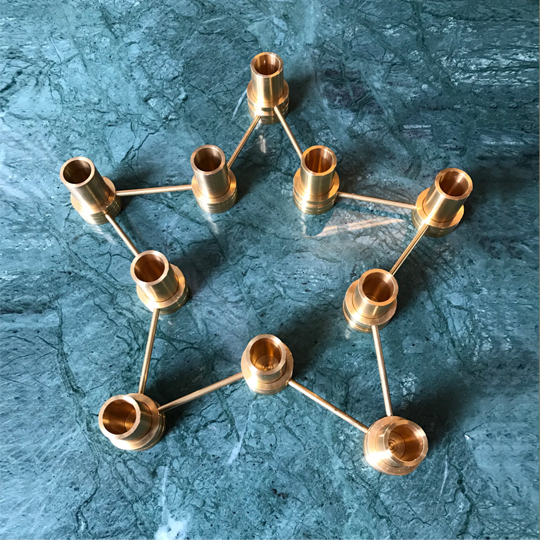 Gold geometric candle holder design on a textured teal background. Elegant and modern decor accent.