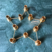 Gold geometric candle holder design on a textured teal background. Elegant and modern decor accent.