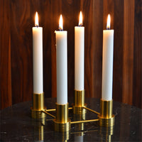 White taper candles in brass holders, exuding elegance with a modern design against a wooden backdrop.