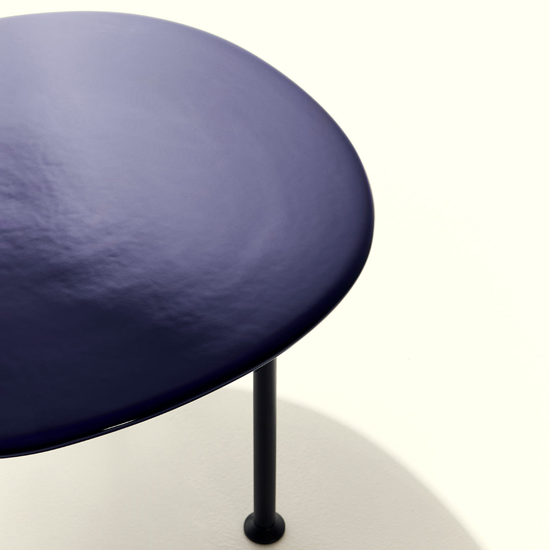 Navy blue round table with a smooth surface and black metal legs, minimalist design on a light background.