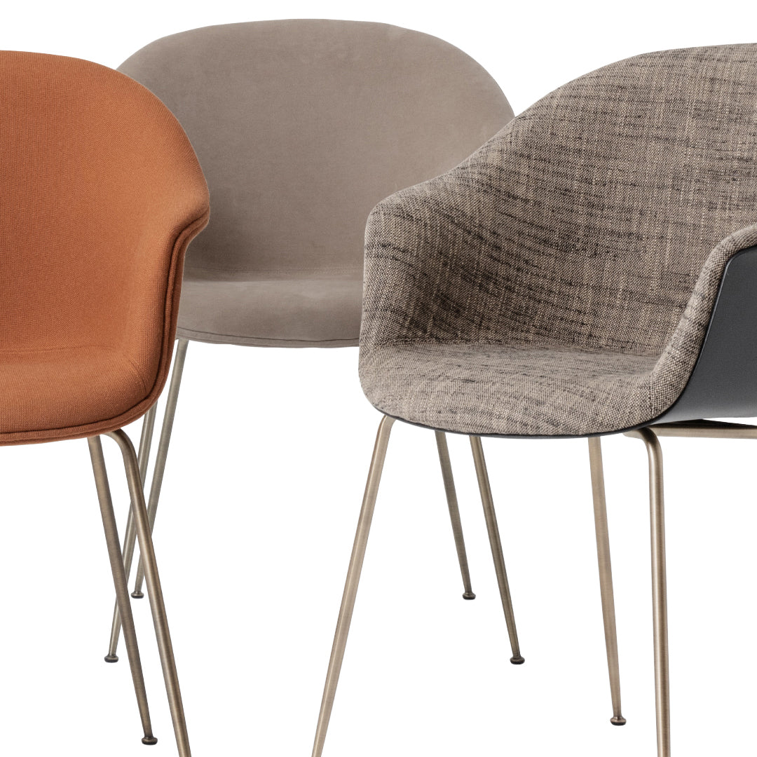 Set of three stylish chairs in burnt orange, grey, and textured fabric patterns with sleek metal legs.