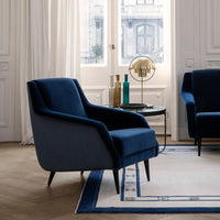 Elegant navy blue armchair with sleek lines, set against a neutral-toned room and patterned area rug.