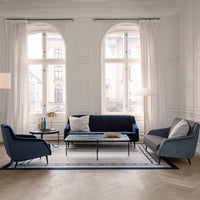 Sleek navy blue and soft gray upholstery with a geometric rug design in a bright, airy living room setting.