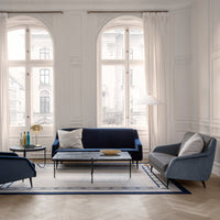 Navy blue and light gray sofas with a geometric patterned rug in a bright, airy room with white walls and large windows.