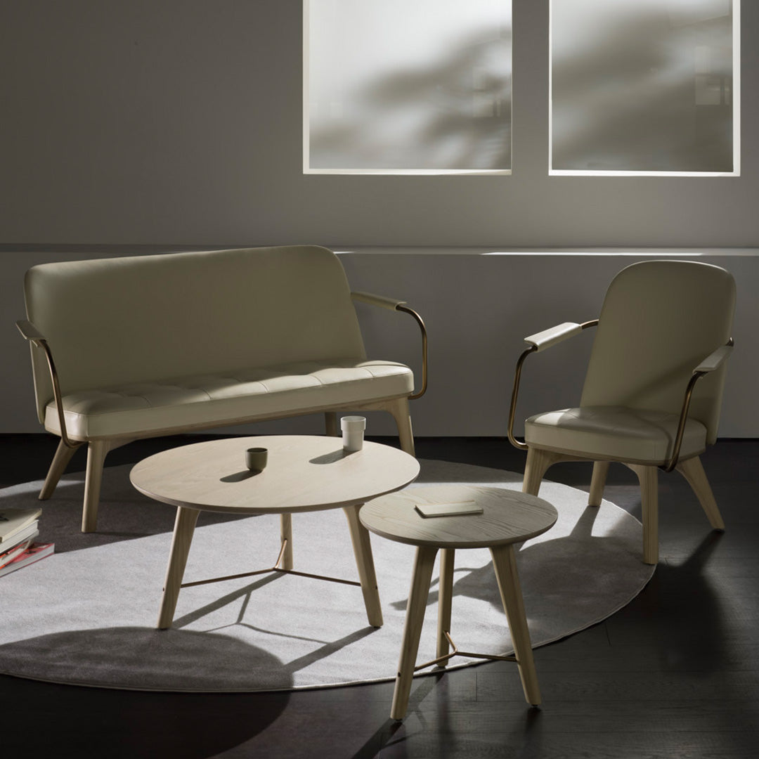 "Light beige sofa set with modern curves on a circular gray rug, complemented by natural wood accents."