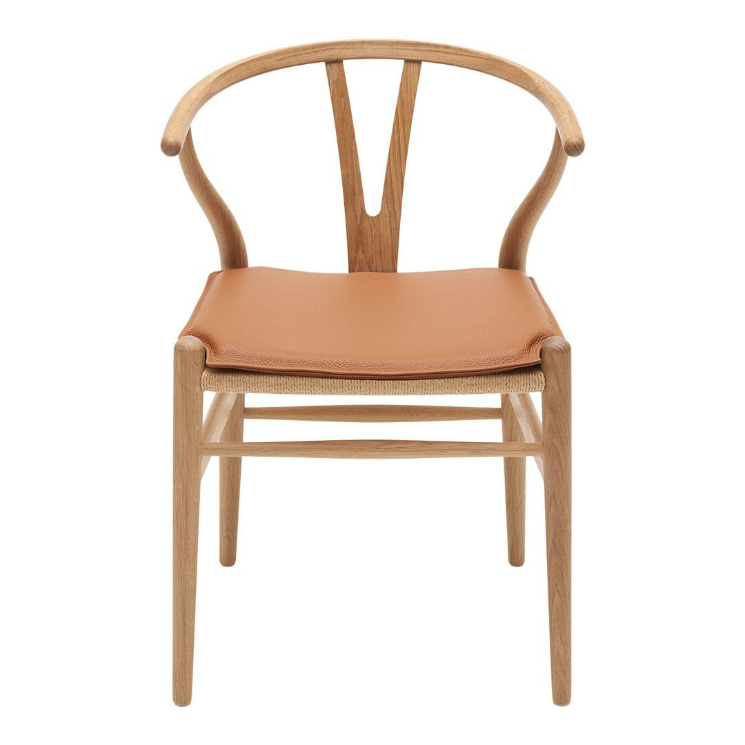 Natural wood chair with a light oak finish and a warm tan leather seat, featuring a minimalist design.