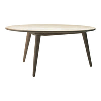 Round wooden table with a light natural finish and tapered brown legs, showcasing a minimalist design.