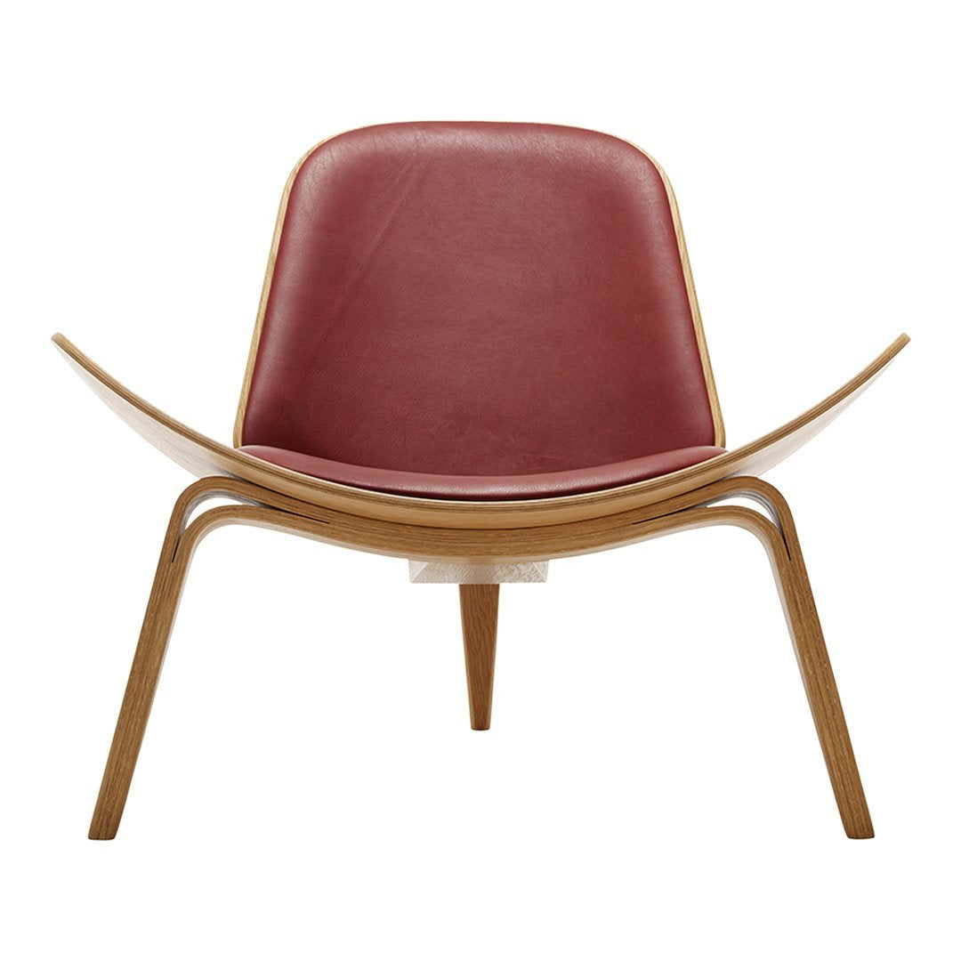 Modern chair with a curved wood frame and burgundy leather seat. Sleek, minimalist design in natural tones.