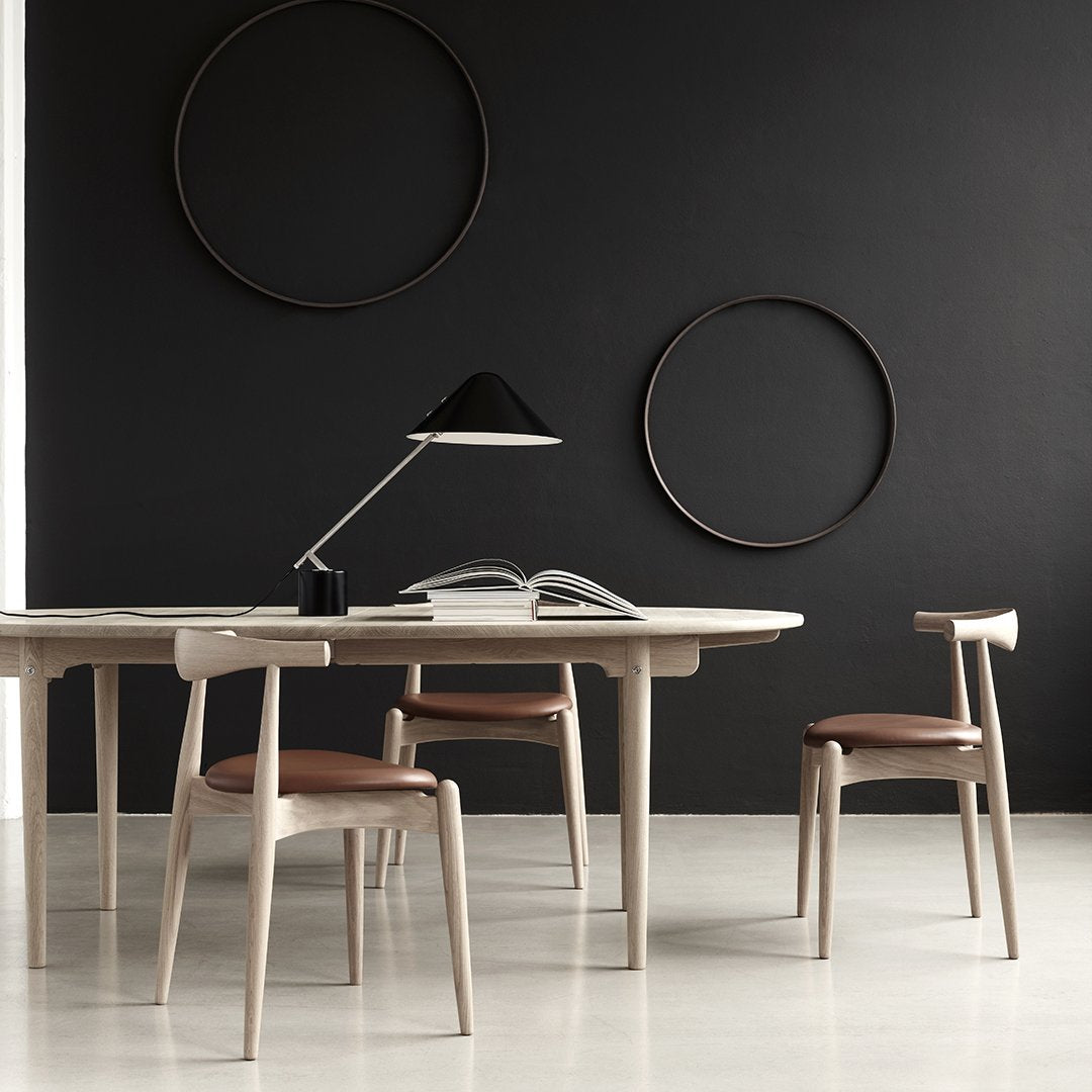 Modern dining set featuring neutral tones with light wood and brown accents against a sleek black wall.