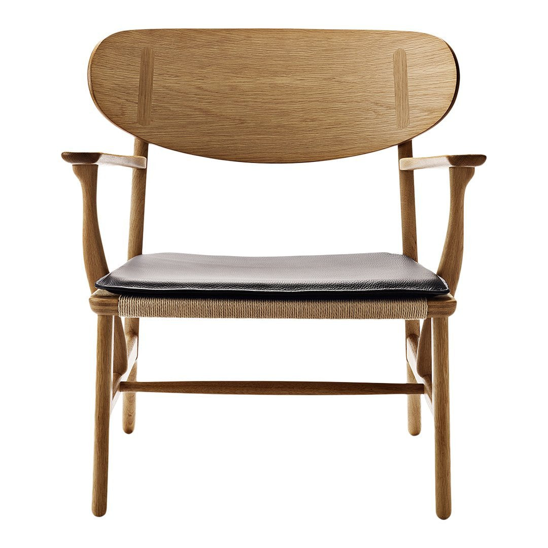 Light oak wood chair with a black leather seat and minimalist design. Elegant curves and clean lines.