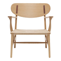 Wooden chair with a light oak finish, featuring a smooth grain and contrasting dark leather accents on the backrest.