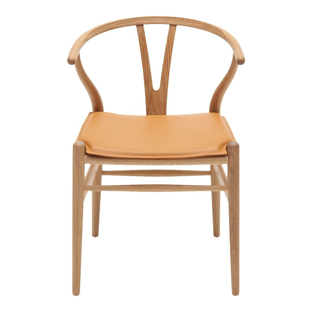 Light wood chair with a natural finish and a tan leather seat, featuring a minimalist design and elegant curves.