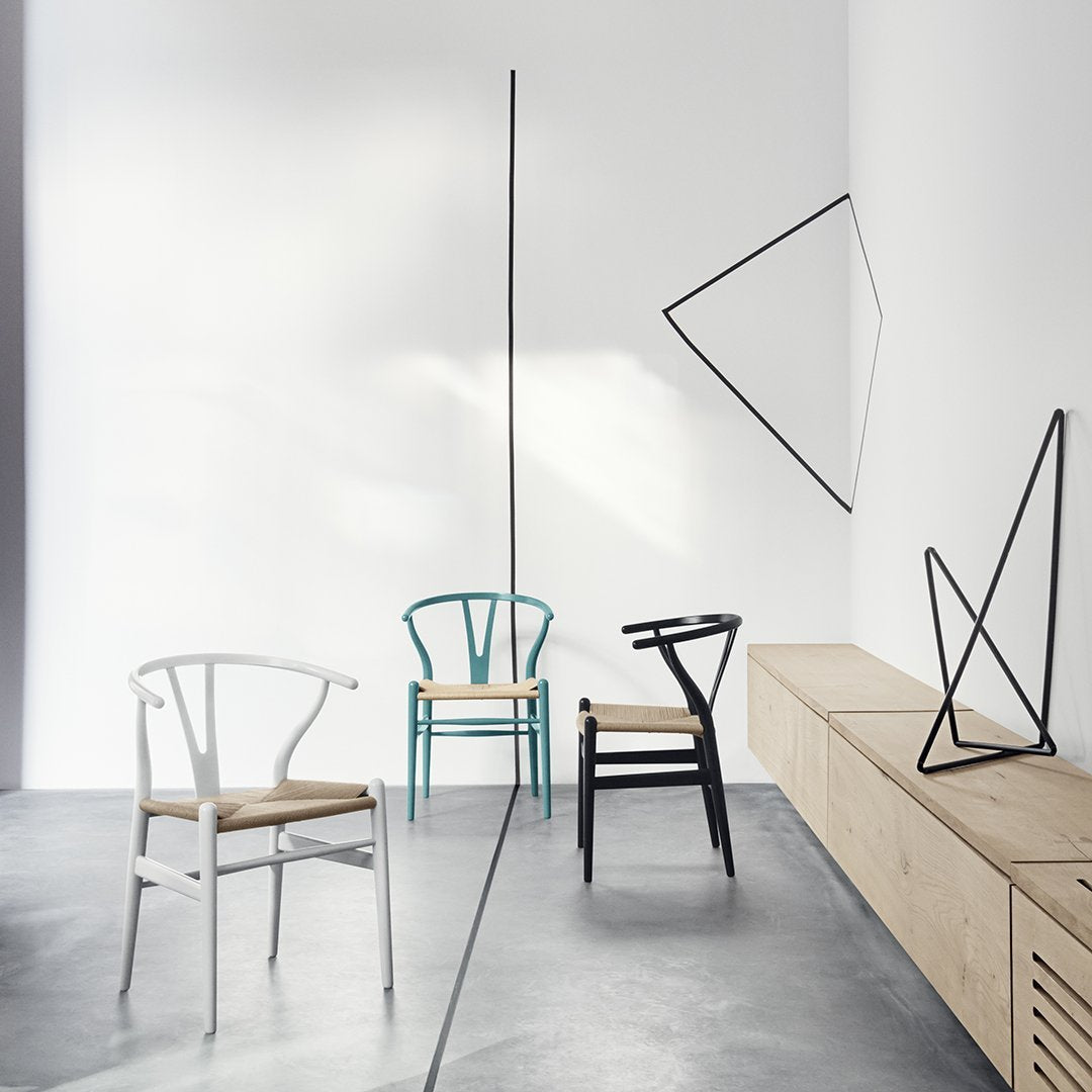 Colorful chairs in white, teal, black, and natural wood with minimalist geometric patterns in a modern setting.