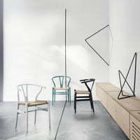 Colorful chairs in white, teal, black, and natural wood with minimalist geometric patterns in a modern setting.