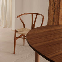 Natural wood tones with a smooth finish, paired with a woven beige seat, create a cozy, minimalist dining setup.