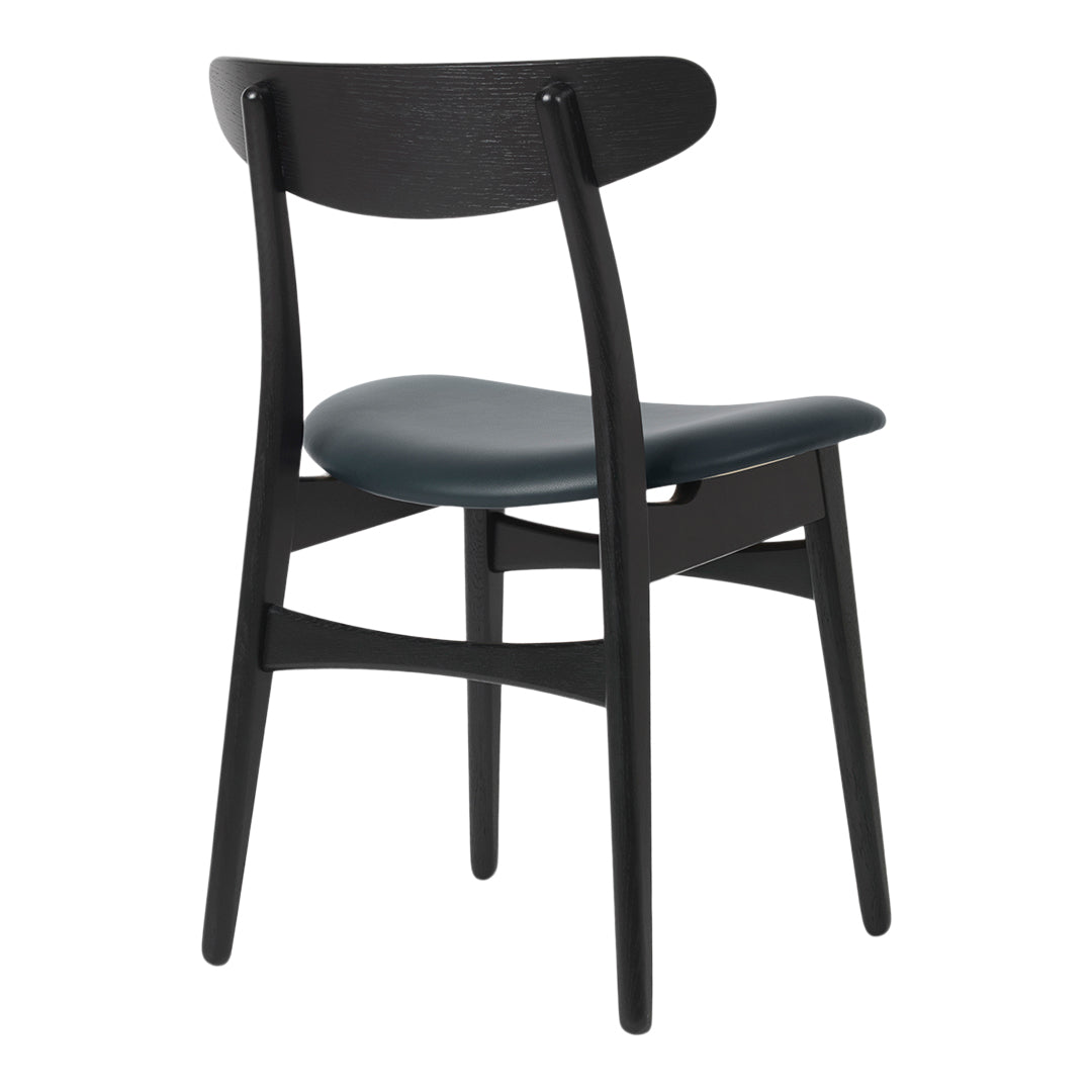 Black wooden chair with a sleek dark green seat, showcasing a minimalist design and smooth finish.