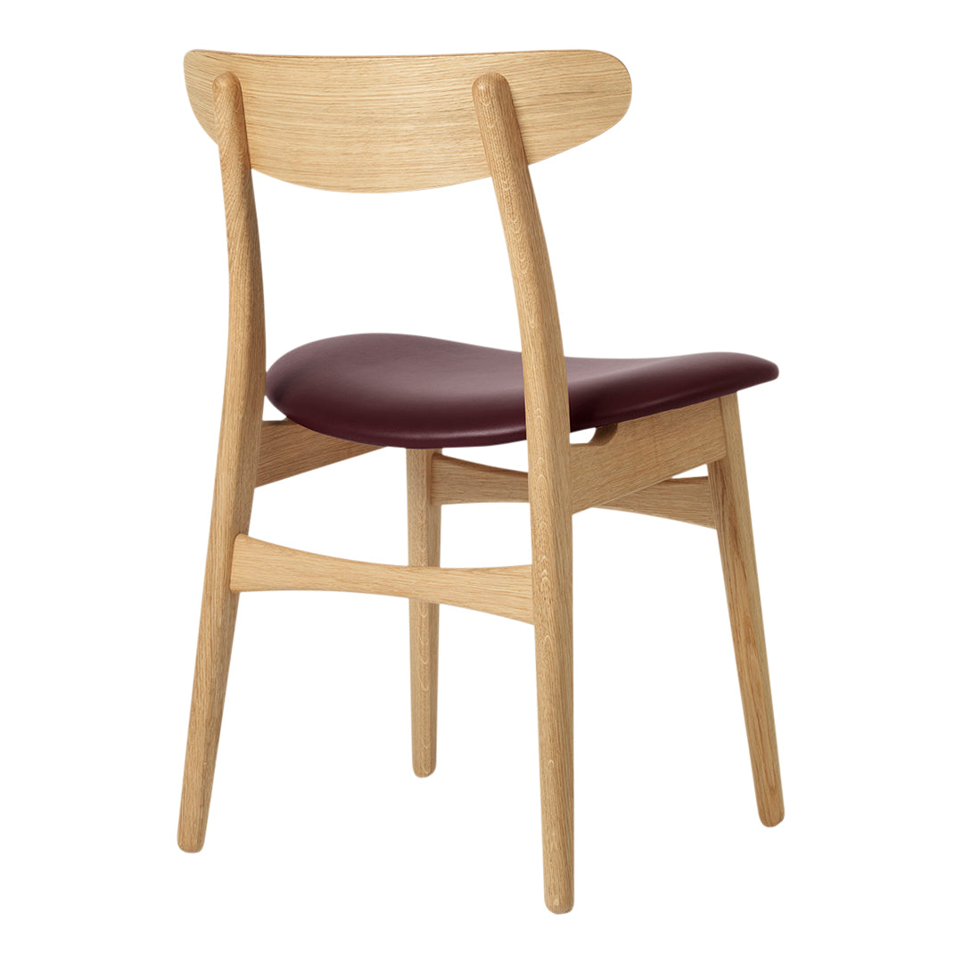 Wooden chair with a natural finish and a burgundy seat, showcasing a simple and modern design.