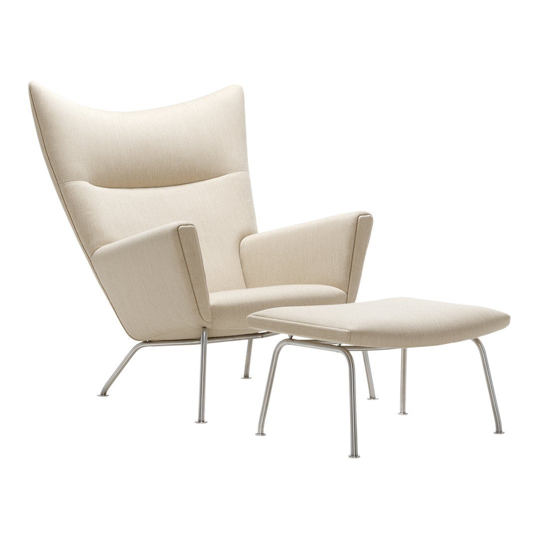 Cream-colored lounge chair with subtle curves and a matching ottoman on sleek metal legs. Perfect for modern decor.