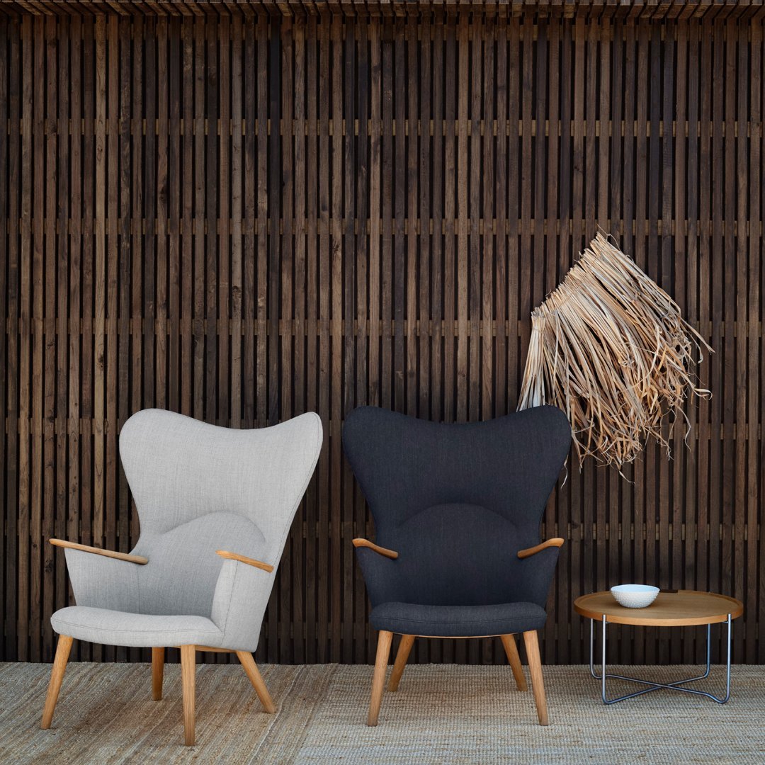 Gray and black armchairs with wooden legs, set against a textured wooden backdrop. Elegant, modern design.