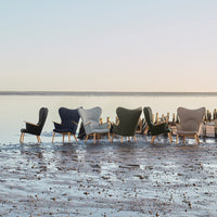 Set of designer chairs in grey, navy, green, and beige with modern patterns against a serene water backdrop.