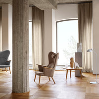 Modern living space featuring muted gray and beige armchairs, wooden flooring, and neutral curtains for a cozy atmosphere.
