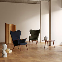 "Two modern armchairs in deep blue and olive green, set against a light backdrop with wooden accents."