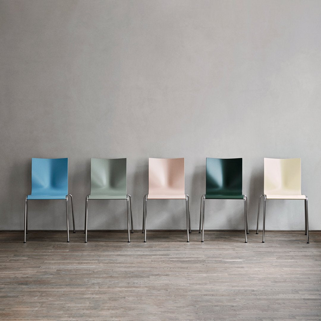 Set of five modern chairs in blue, green, pink, dark green, and cream with smooth, minimalist designs.