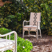 Beige outdoor chair with a black geometric pattern against lush greenery. Perfect for stylish patio decor.