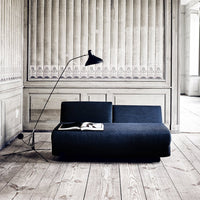 "Modern dark blue sofa with a sleek design against light wood paneling and a neutral backdrop."
