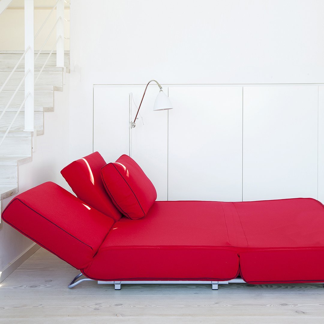 Red adjustable sofa with a sleek design and smooth texture, featuring bold, solid color cushions.
