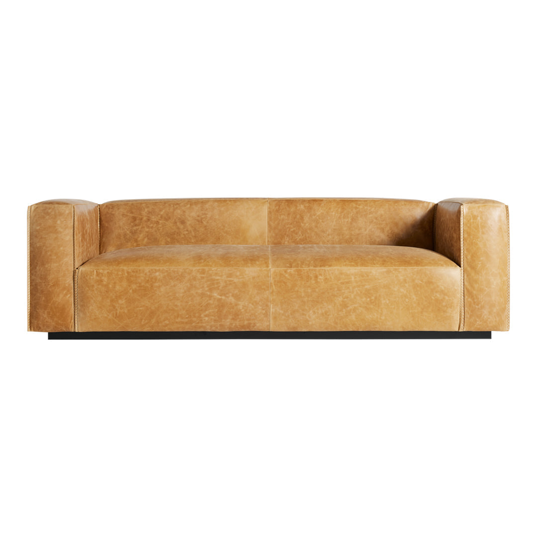 Sleek beige leather sofa with a smooth texture and minimalistic design, featuring rounded armrests and a low profile.