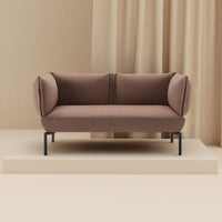 Brown upholstered sofa with rounded arms, featuring a textured pattern, set against a neutral backdrop.