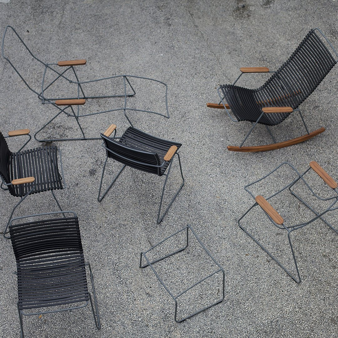 Assorted black woven chairs and stools with wooden armrests, showcasing modern minimalist design on a textured surface.