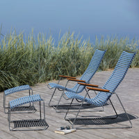 Blue-striped outdoor lounge chairs with natural wood accents, set against a backdrop of tall green grass.