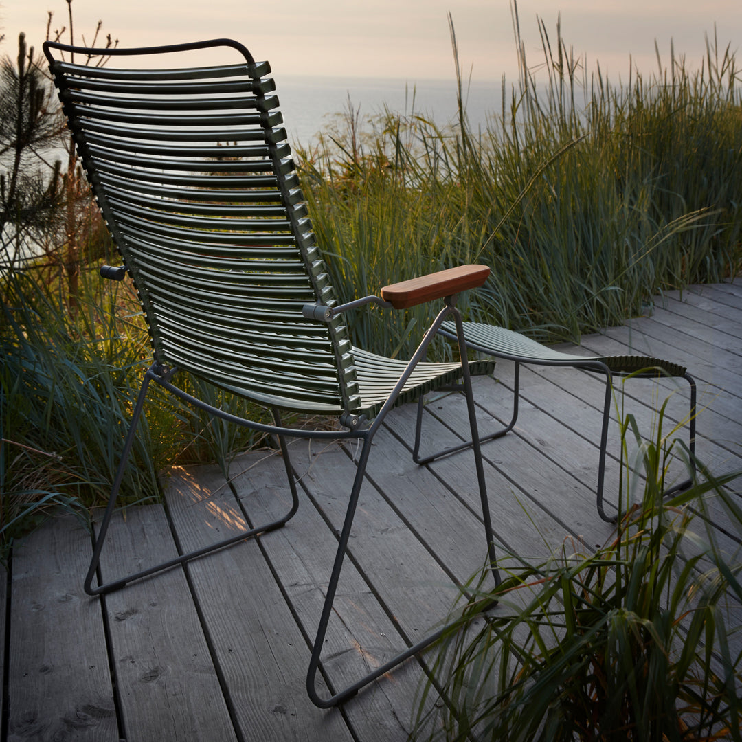 "Modern green striped outdoor chair with wooden armrest against a natural backdrop."