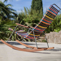 Colorful striped rocking chair with vibrant hues and intricate patterns, set against a sunny outdoor background.