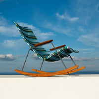 Blue and green striped rocking chair with wooden accents, set against a bright, clear sky backdrop.
