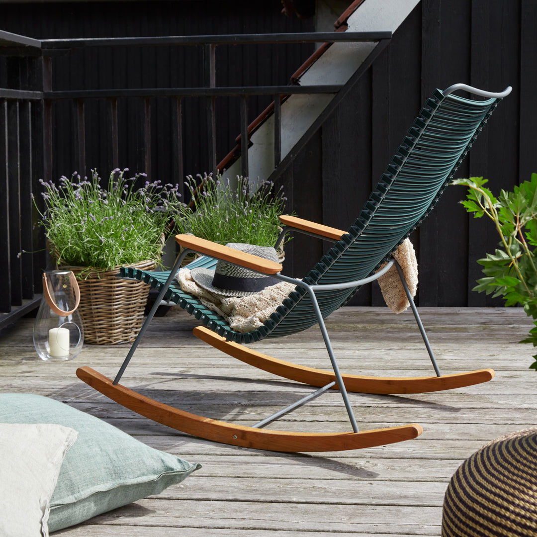 Green and beige rocking chair with elegant wooden accents and distinctive woven pattern, set against a natural backdrop.