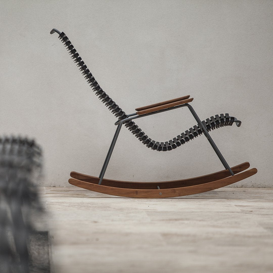 Black spiral accents on a sleek wooden rocking chair against a neutral backdrop, showcasing modern design.
