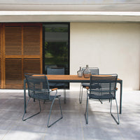Modern outdoor dining set featuring a natural wood table and sleek gray chairs against a neutral backdrop. 
