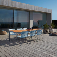 Outdoor dining set featuring a wooden table and light blue chairs against a neutral backdrop and wooden deck.