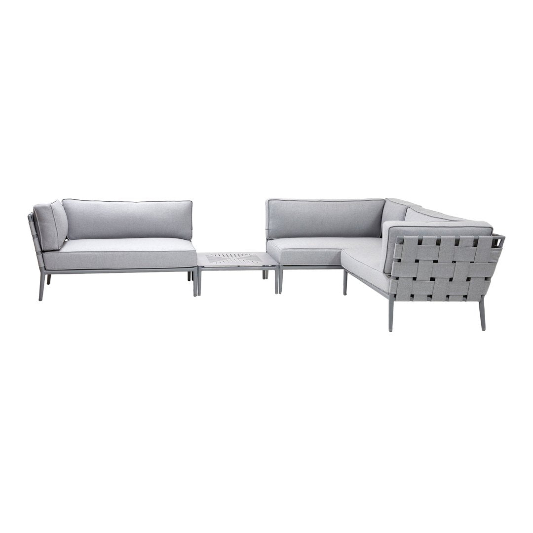 Modern L-shaped sofa set in soft gray fabric with sleek silver accents and minimalist geometric patterns.